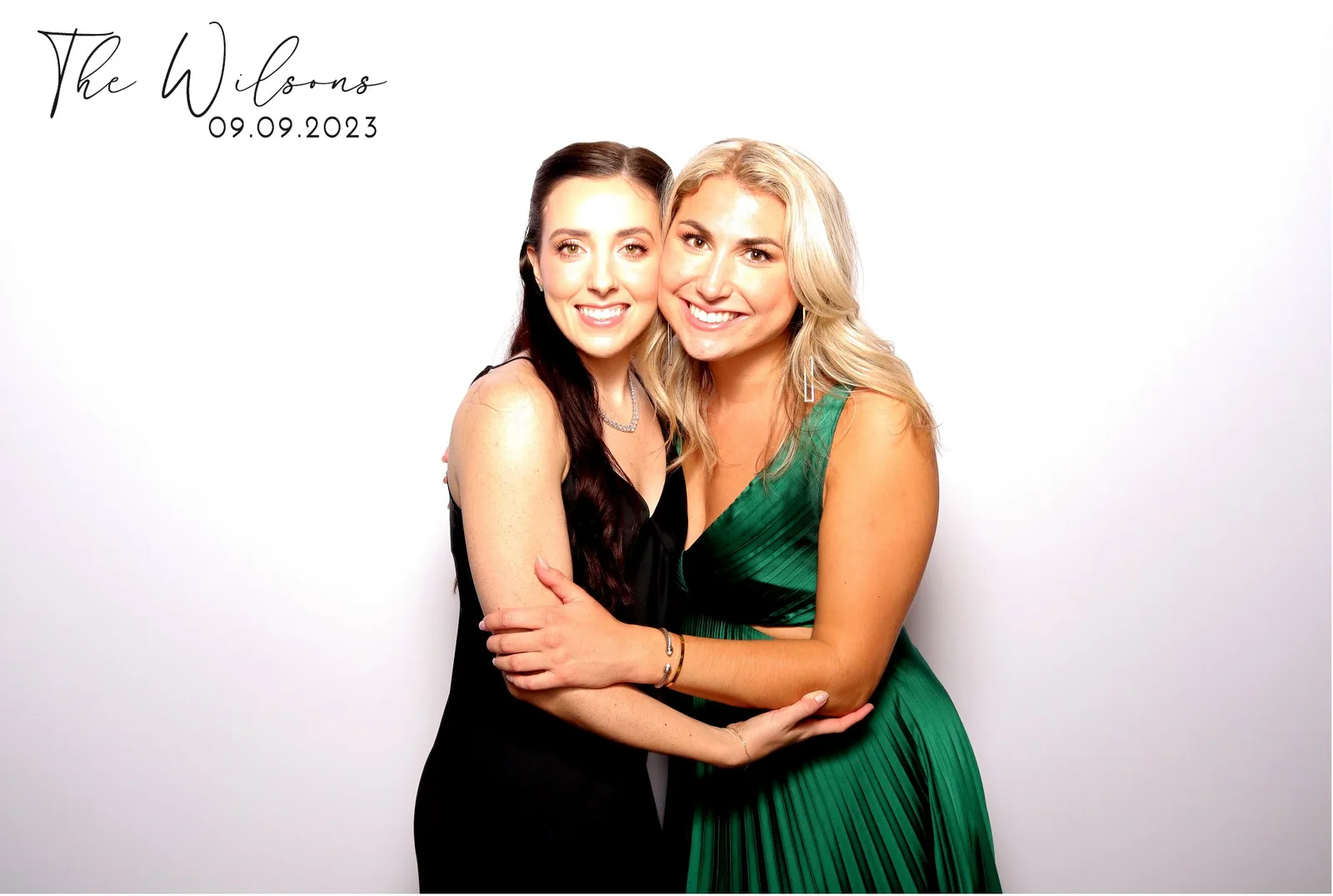 Two guests hugging, emerald dress, color glam