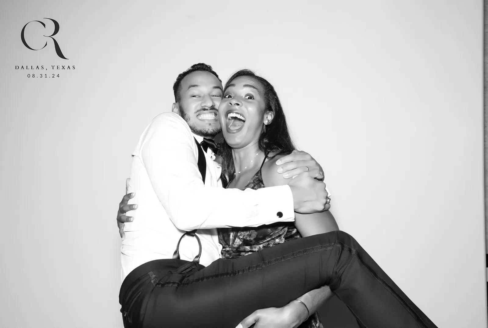 Couple lifted mid-laugh, black and white glam photo booth
