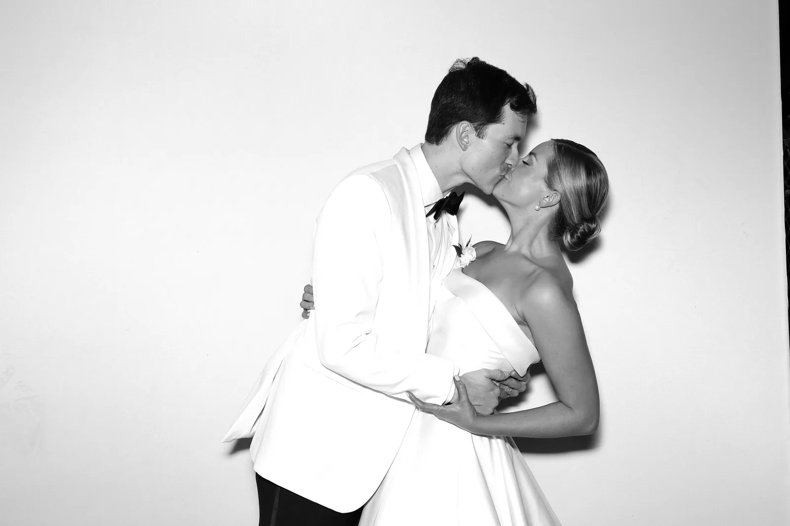 Groom in white tuxedo dipping the bride, black and white glam